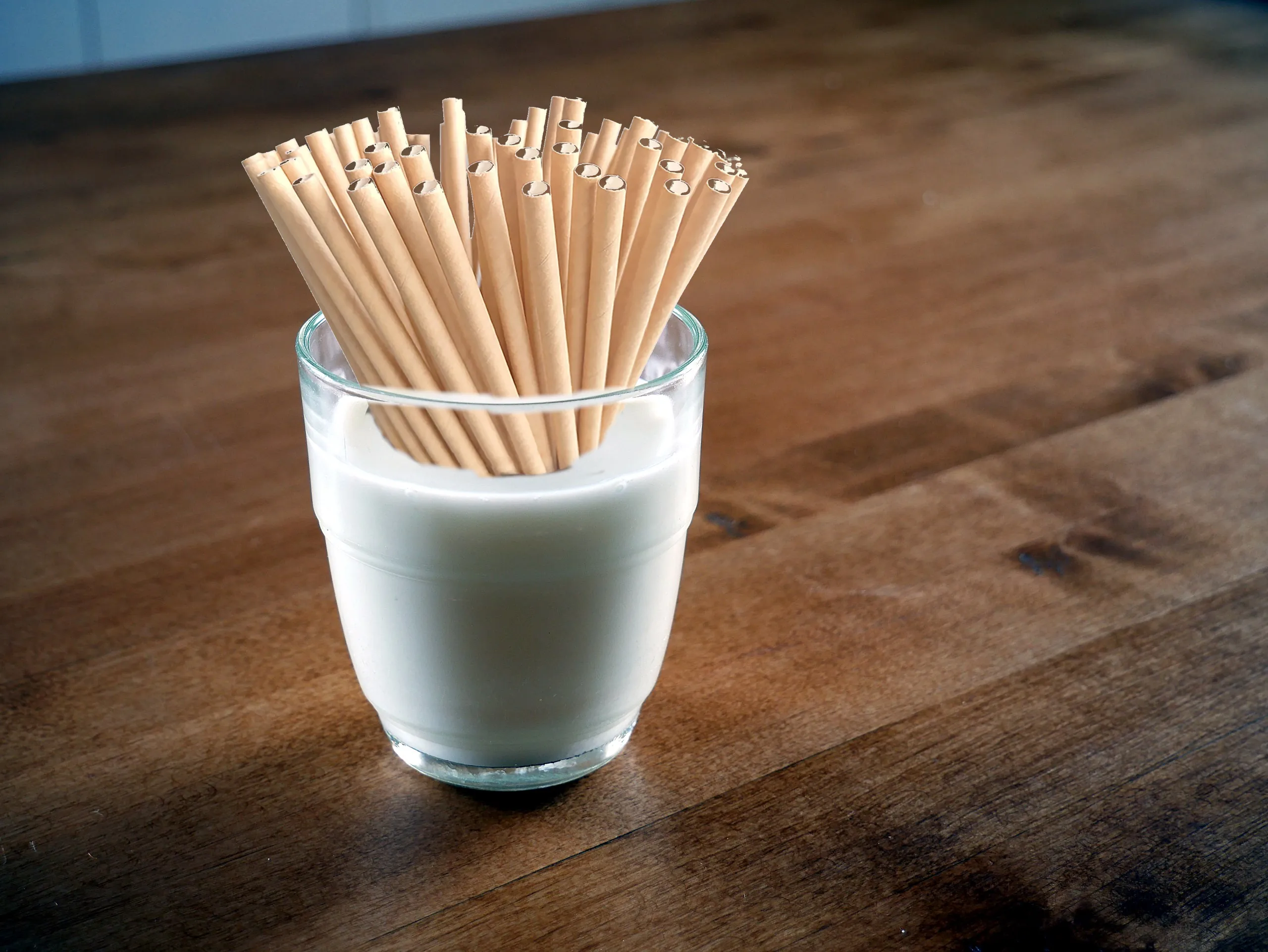 A whole bundle of paper straws in a glass of milk